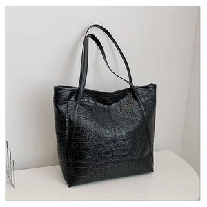 Detail of black crocodile texture on a large tote bag with elegant double shoulder straps