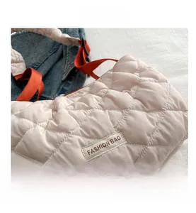 Detail of off-white quilted pillow bag with orange strap and fashion bag logo