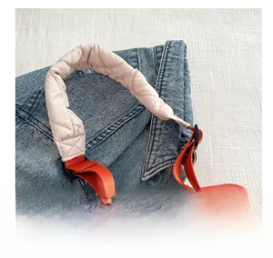 Detail of quilted beige handbag with soft handle and orange nylon adjustable strap