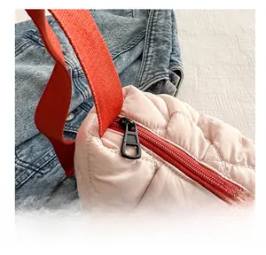 Close-up of pink quilted puffer bag showing smooth black metal zipper and red strap