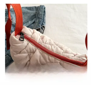 Detail of light pink quilted nylon bag with red zipper and diamond pattern texture