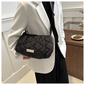 Detail of black quilted puffer crossbody bag with FASHION BAG woven label and nylon strap
