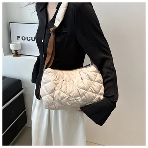 Detail of beige quilted bubble shoulder bag featuring adjustable strap and fashion label