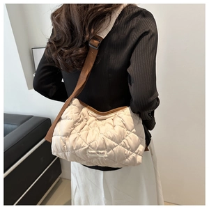 Detail of beige quilted pillow bag with brown adjustable strap and fashion label