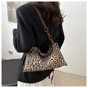 Detail of leopard print hobo bag featuring amber chain strap and premium fabric texture