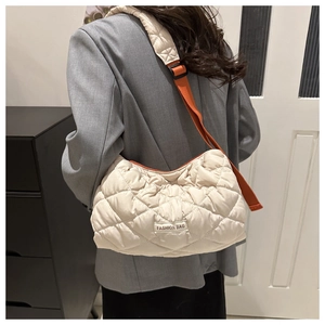 Detail of quilted beige puffer crossbody bag with a vibrant orange adjustable strap
