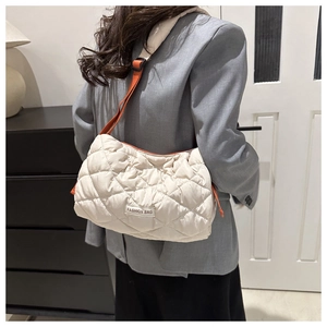 Quilted beige shoulder bag with orange contrast straps and a fashion woven label