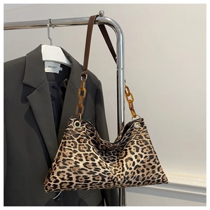 Detail showing amber acrylic chain links and brown leather strap on leopard print tote