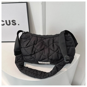 Detail of black quilted puffer bag with adjustable wide strap and fashion logo tag