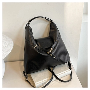 Close-up of black leather tote bag featuring golden buckles and adjustable straps