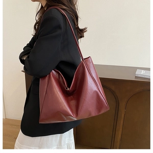 Deep red large capacity tote bag worn by model in a minimalist setting for daily commute