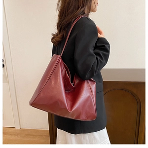 Close-up of a burgundy tote bag featuring premium glossy leather texture and shoulder strap