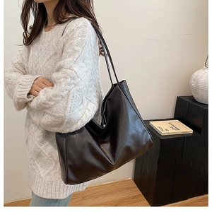 Detail of a large black PU leather hobo bag showing its smooth texture and casual design