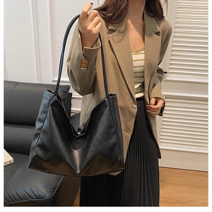 Detail showing high-capacity black tote bag with soft leather texture and shoulder strap