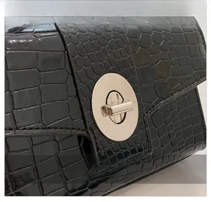 Close-up of crocodile pattern faux leather and round metallic twist lock on the handbag