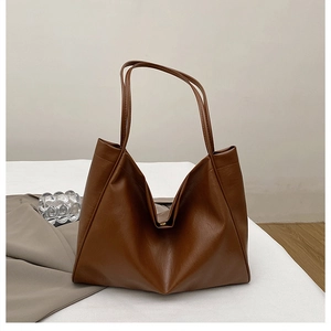 Close-up of a large brown faux leather tote bag showing the magnetic buckle and texture