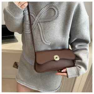 Close-up of brown PU leather shoulder bag with golden round woven clasp detail
