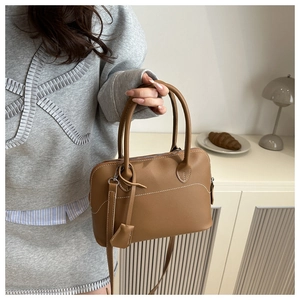 Close-up of brown vintage matte leather bag with contrast stitching and dual handles