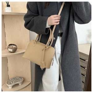 Chic beige matte leather shell handbag styled with a grey wool coat for daily commuting
