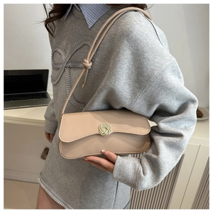 Detail of apricot shoulder bag featuring a golden knotted metal buckle and smooth leather