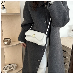 Chic white leather shoulder bag featuring a decorative gold metal twist buckle on a flap