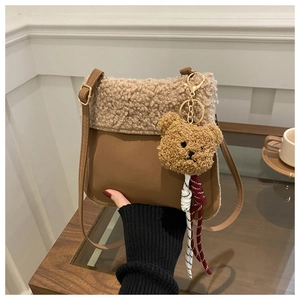 Détail du sac seau en peau de mouton avec base en similicuir brun et breloque ours