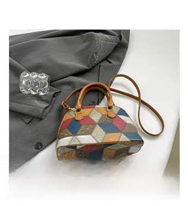 Detailed macro view of color-block patchwork leather and gold hardware on shell bag
