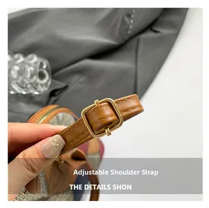 Close-up of adjustable brown leather shoulder strap with gold metal buckle on a shell bag