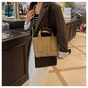 Detail of khaki leather bucket bag with gold rivets and adjustable strap in a retro bar