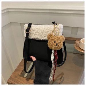 Détail du sac seau noir avec bordure en fausse fourrure blanche et pendentif ours brun