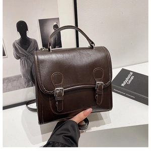 Close-up of vintage brown leather satchel with silver buckles and textured PU finish