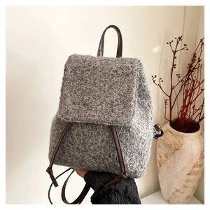 Detail of wool texture and brown leather strap on a minimalist grey bucket backpack
