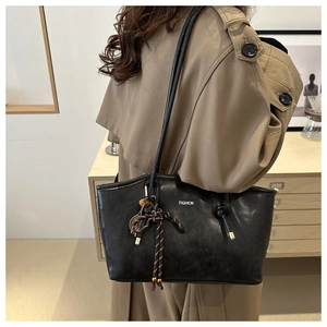 Grande borsa tote in pelle nera con testo FASHION e ciondolo a righe su trench kaki