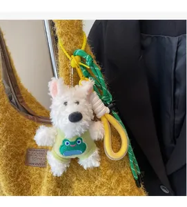 Cute white plush puppy charm in green frog outfit on a fuzzy yellow shoulder tote bag