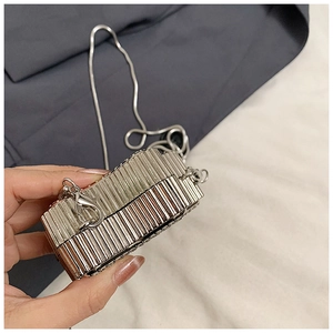 Gros plan d'une mini pochette de soirée argentée à rayures métalliques et fine chaîne