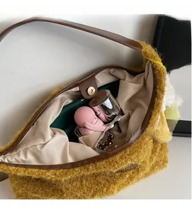 Detail of spacious yellow plush shoulder bag with brown leather trim and magnetic closure