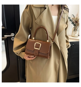 Close-up of vintage brown patent leather handbag with a large gold square buckle