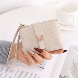 Close-up of litchi grain cream wallet with C-shaped metal buckle and wrist strap