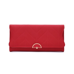 Detail of red leather wallet featuring leaf stitching and gold flower snap closure