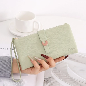Detail of mint green lychee grain leather wallet with pink C-buckle and hand strap