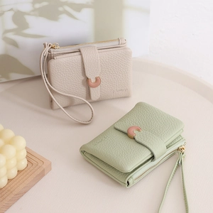 Detailed view of beige and green pebbled leather wallets with elegant C-shape metal buckles