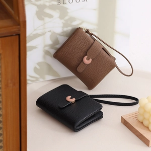 Detail of short lychee grain PU leather wallets in black and brown with metal buckles