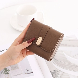 Brown litchi grain leather wallet with gold twist lock held in a lifestyle setting