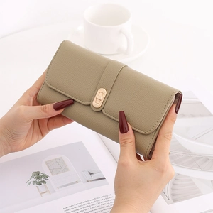 Detail of khaki pebbled leather long wallet with gold Lucky buckle held by hands