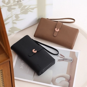 Detail showing two leather wristlet wallets with C-buckle closures and lychee texture