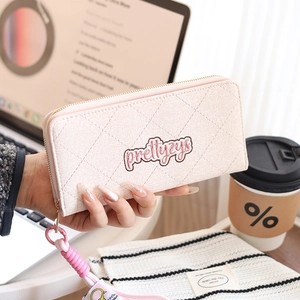 Close-up of pink quilted leather long wallet with embroidered logo and braided wrist strap