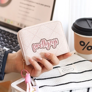 Gros plan sur un portefeuille court matelassé rose avec fermeture éclair et broderie