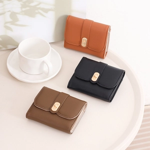 Three-fold leather wallets in orange, black, and dark brown with golden twist lock detail
