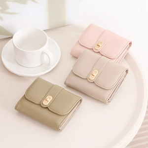 Three colors of compact tri-fold wallets with metallic twist locks on a white table
