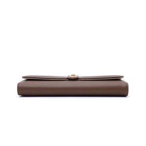 Detail of deep brown long wallet showing pebbled leather texture and gold buckle